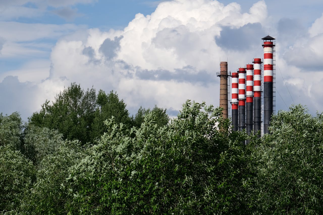 Scenic view of factory chimneys surrounded by lush trees under a blue sky in Minsk, Belarus.