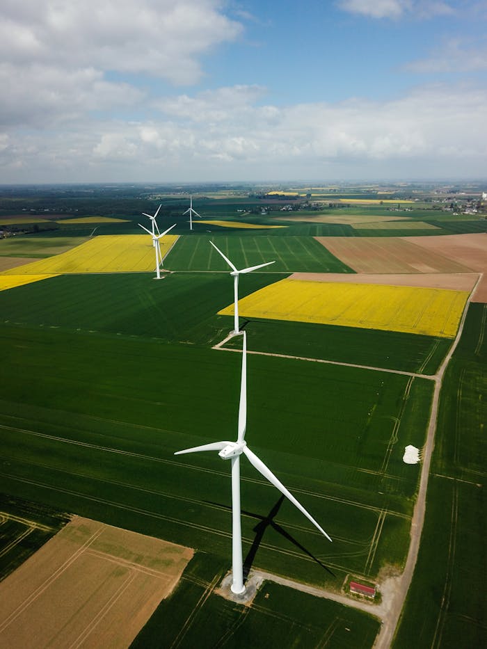 Drone shot of wind turbines in vibrant agricultural fields in France.